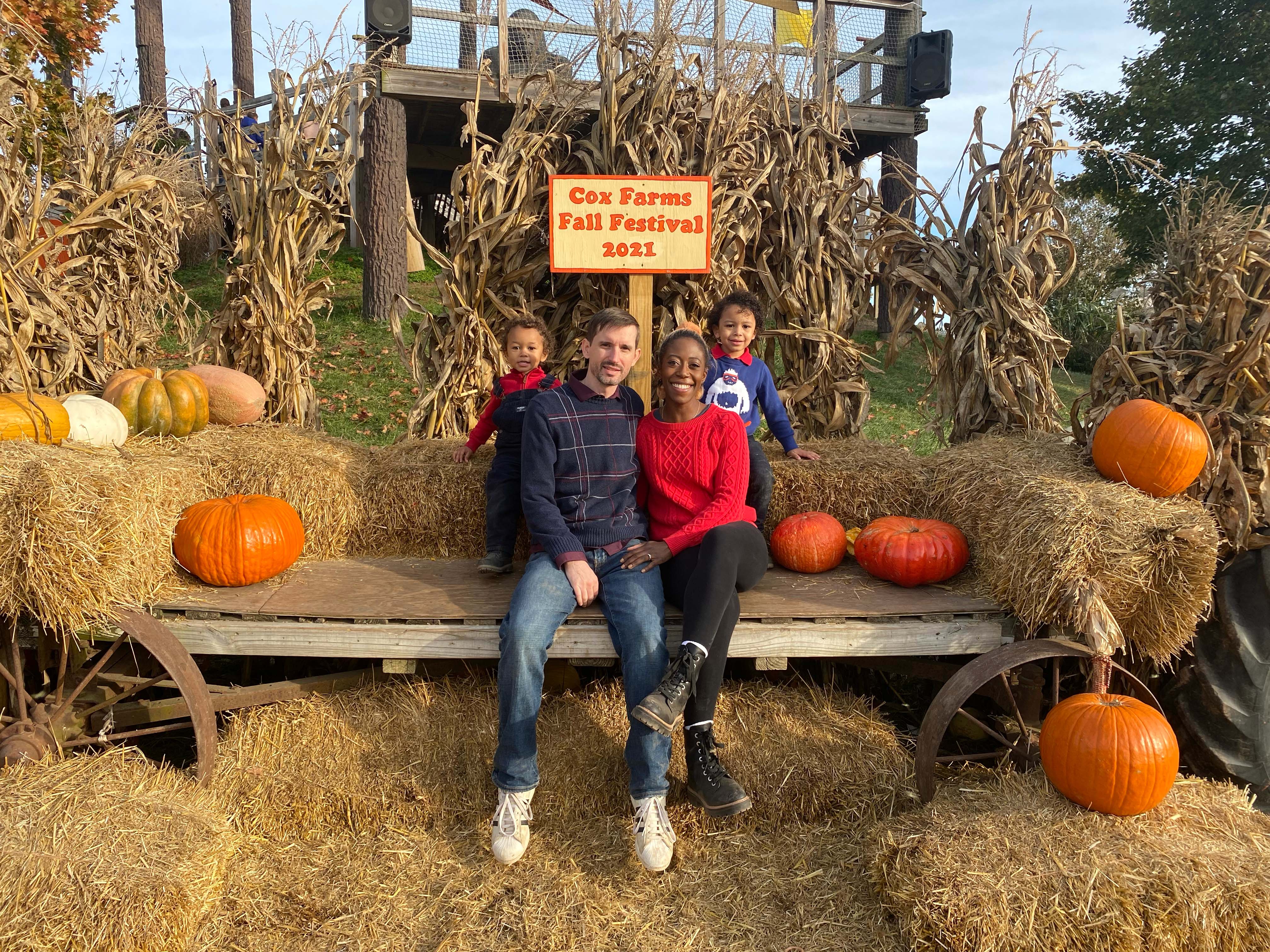 Interracial family of four posing with hay bale