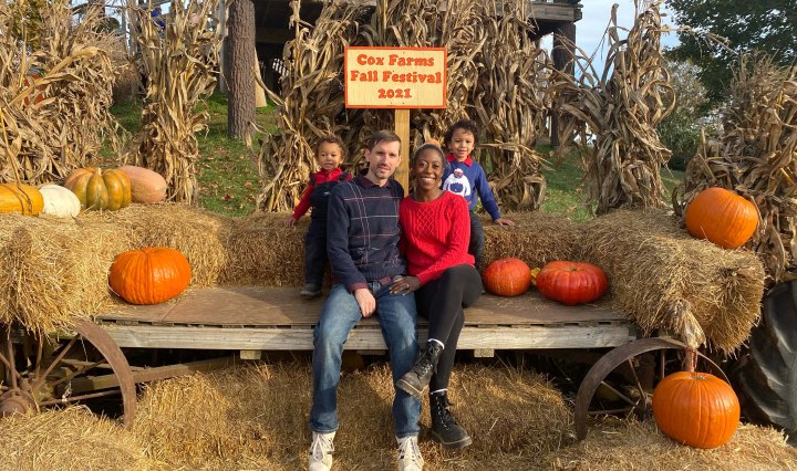 Interracial family of four posing with hay bale
