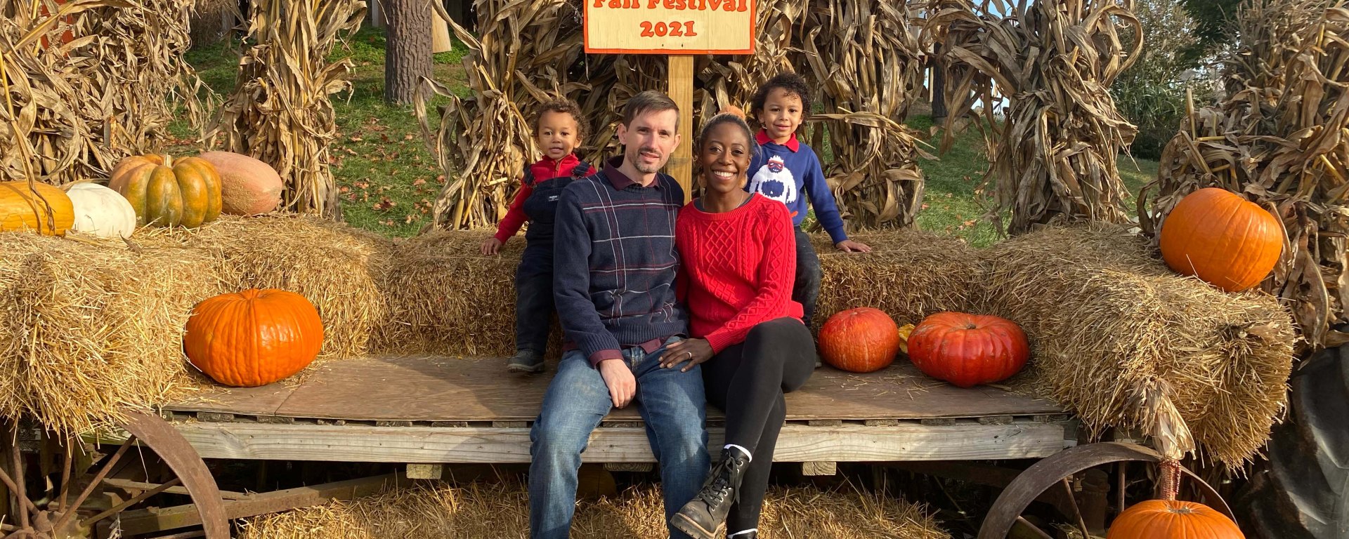 Interracial family of four posing with hay bale